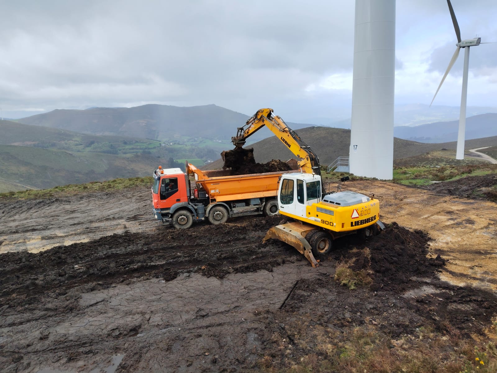 Excavadora y camión en trabajos de infraestructura junto a aerogeneradores