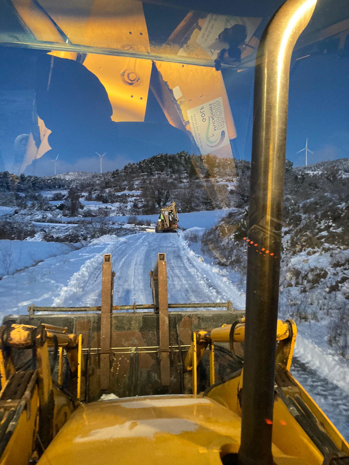 Maquinaria en un camino nevado de parque eólico, vista desde la cabina